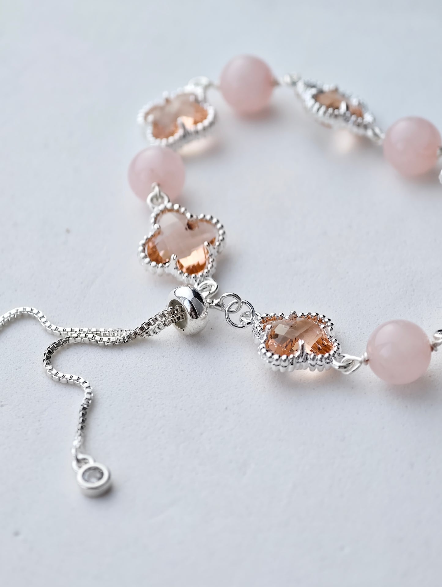 Necklace with pink beads and silver clasps on a light gray background