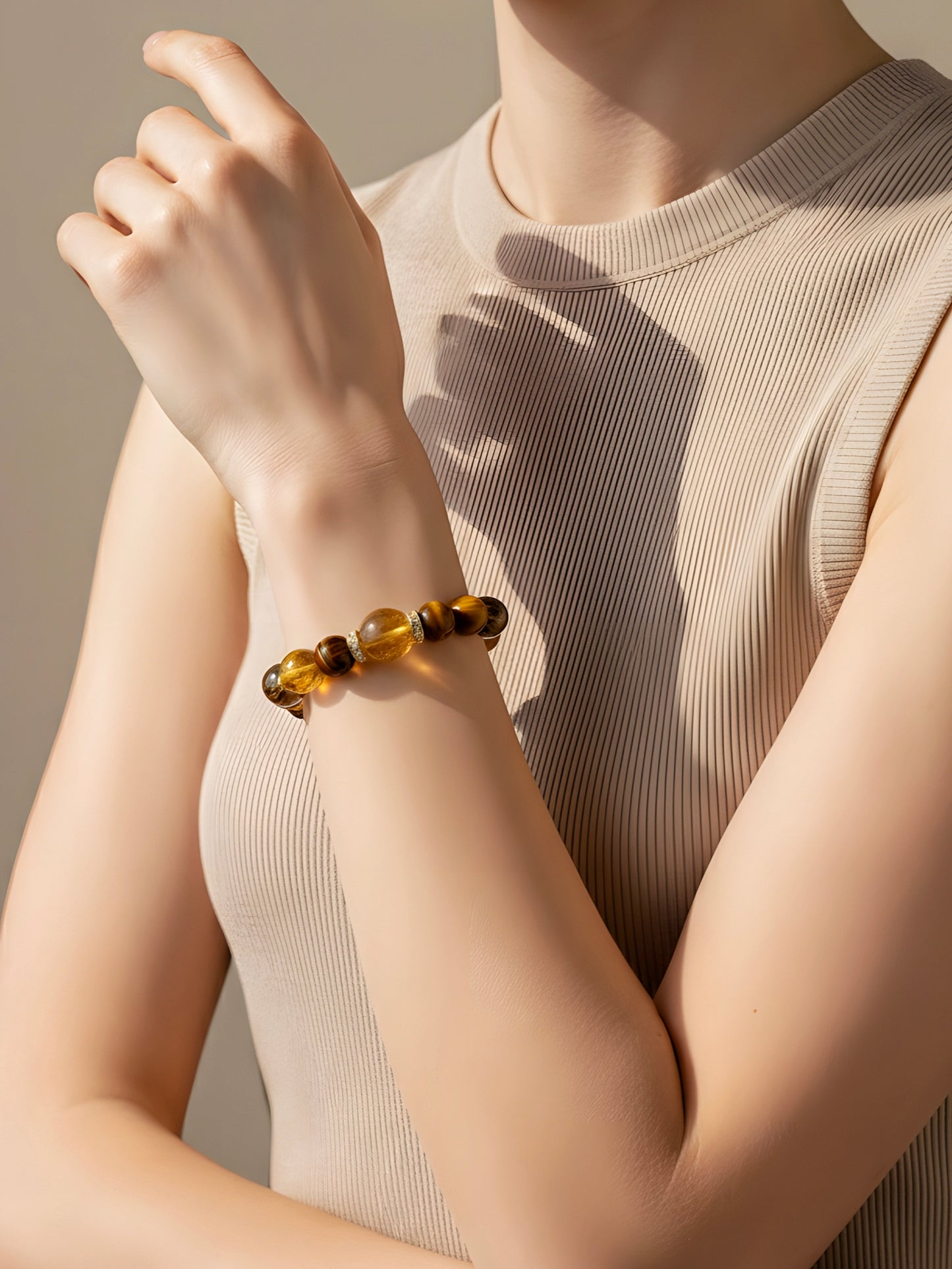 Person wearing a bracelet with three beads on a neutral background
