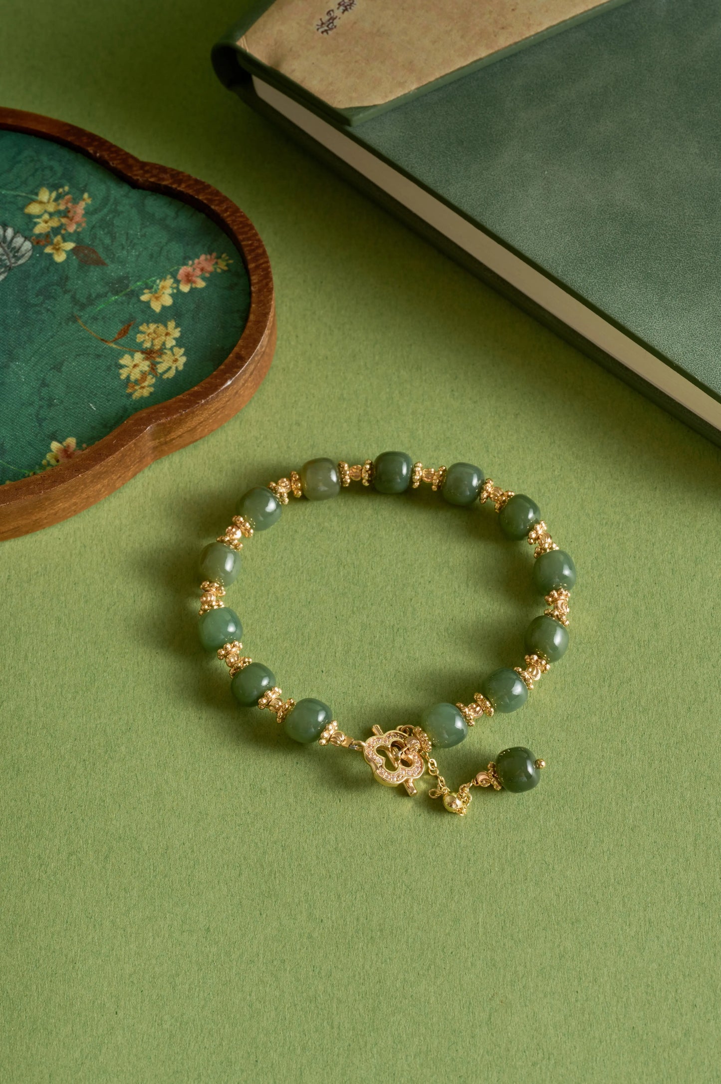 Green beaded bracelet with gold accents on a green surface