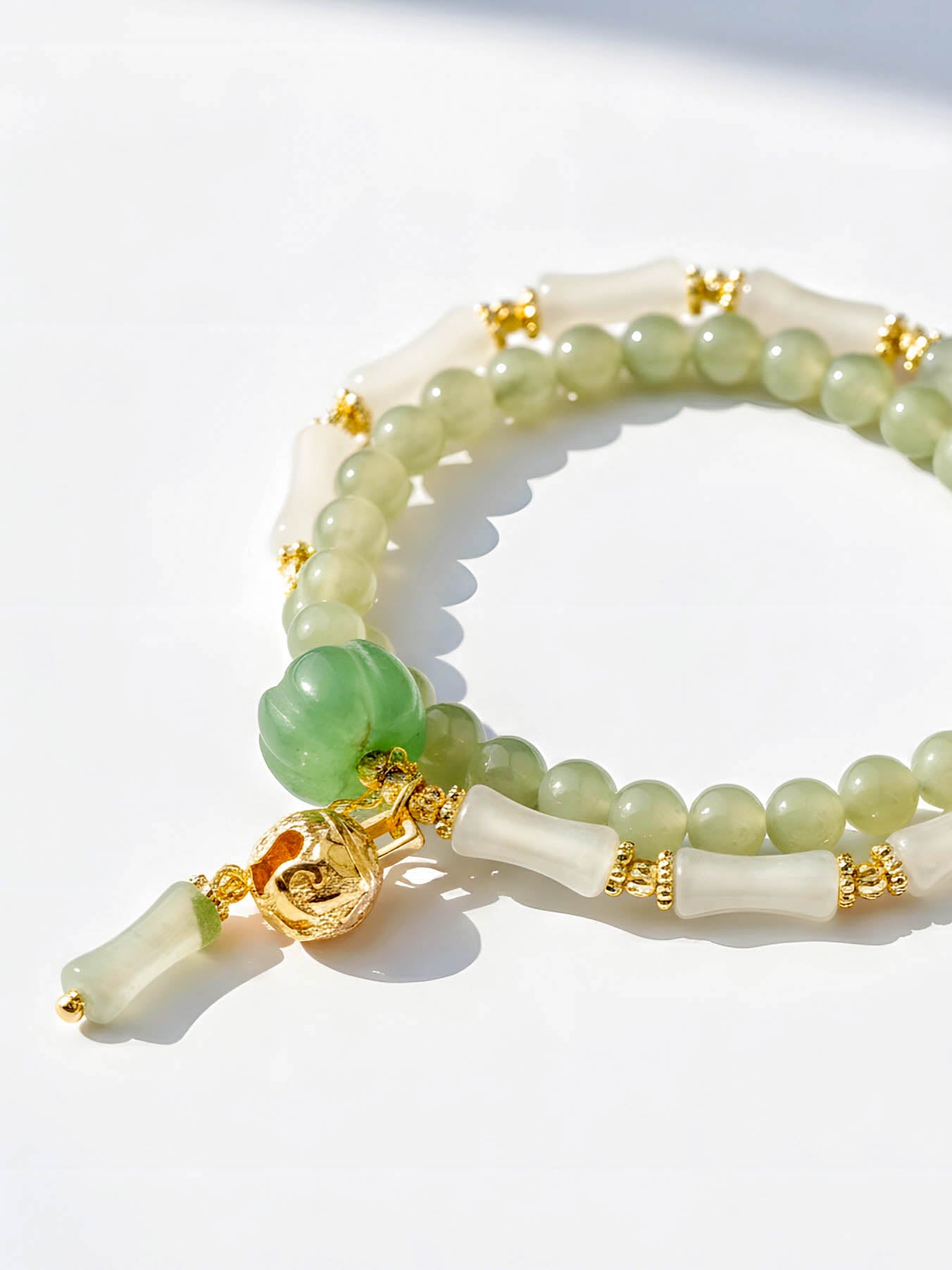 Beaded bracelet with green and gold accents on a white background