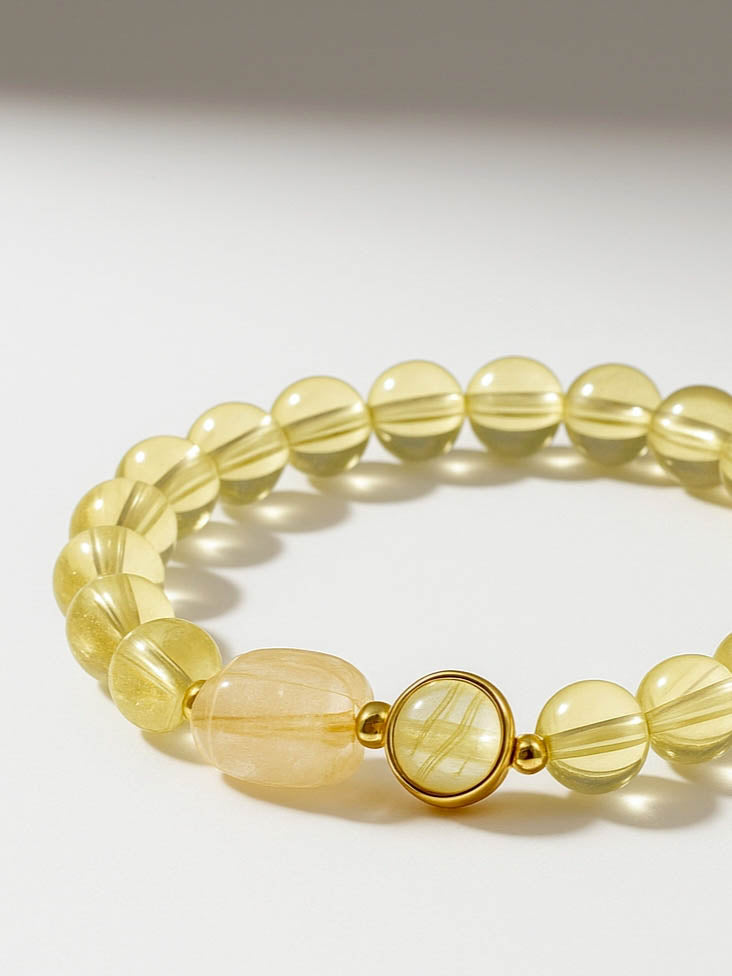 Yellow beaded bracelet with a gold clasp on a light gray background
