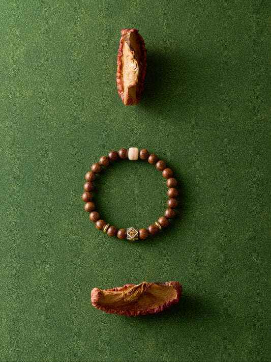 Wooden bracelet with two dried fruits on a green background