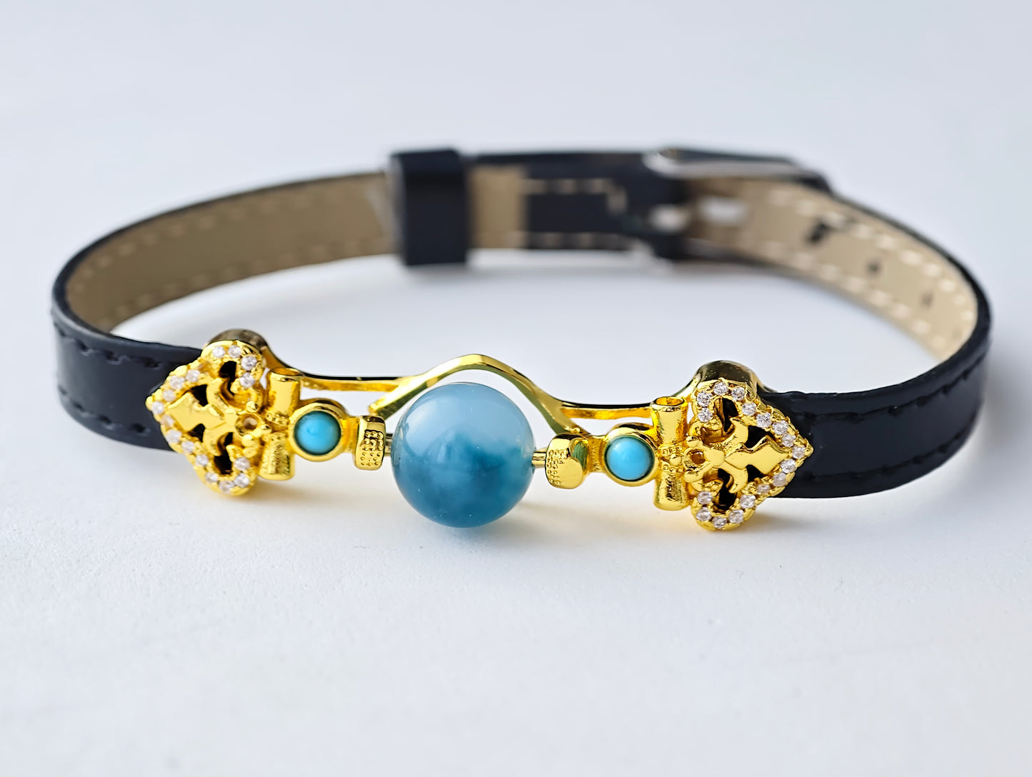 Decorative dog collar with gold accents and a blue gemstone on a white background