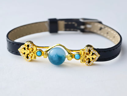 Decorative dog collar with gold accents and a blue gemstone on a white background
