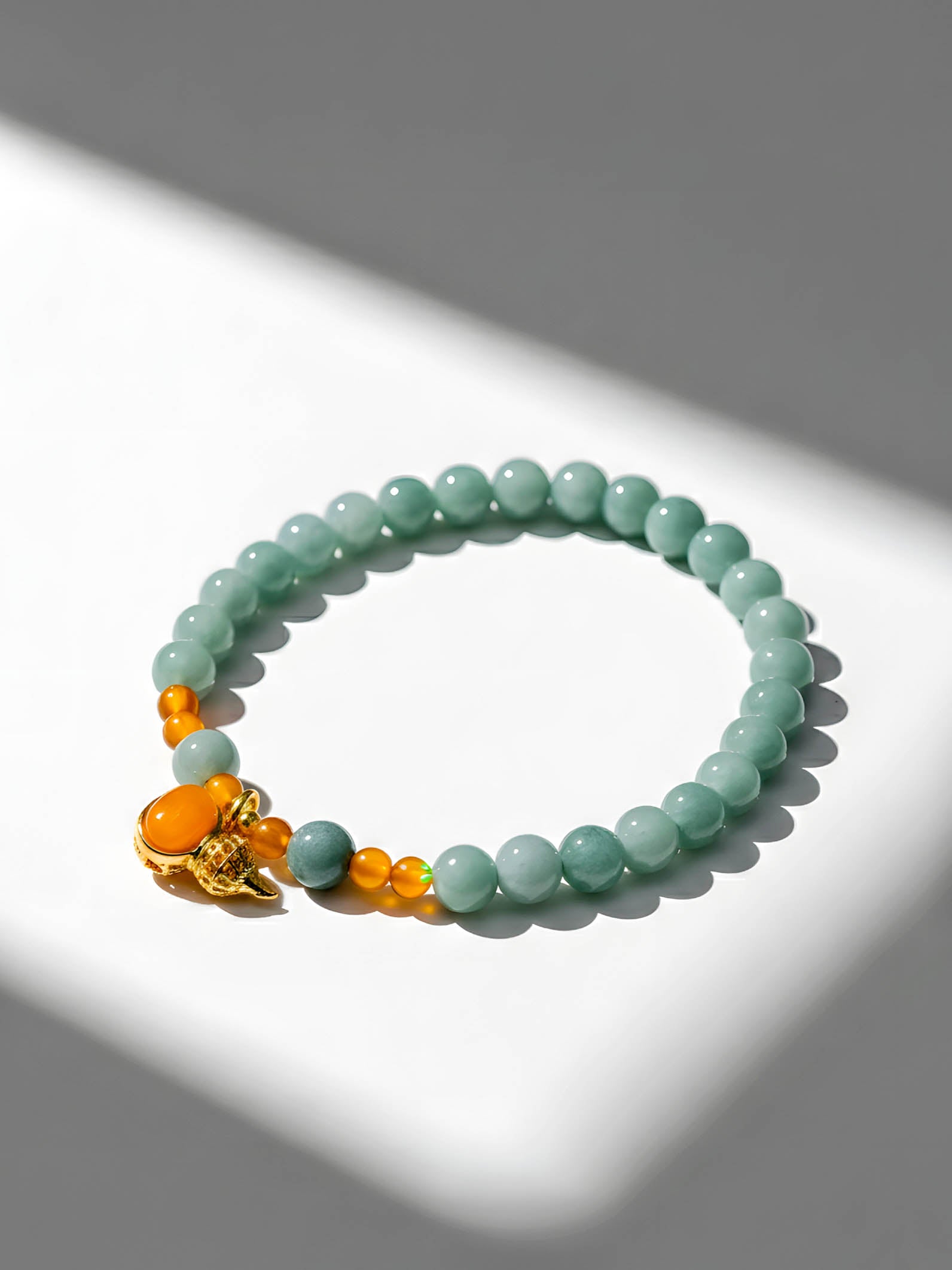 Green beaded bracelet with gold and orange accents on a white background