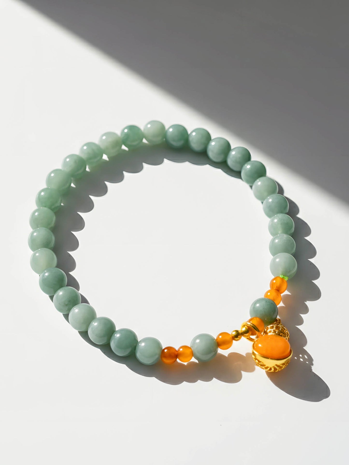 Green beaded bracelet with orange accents on a white background