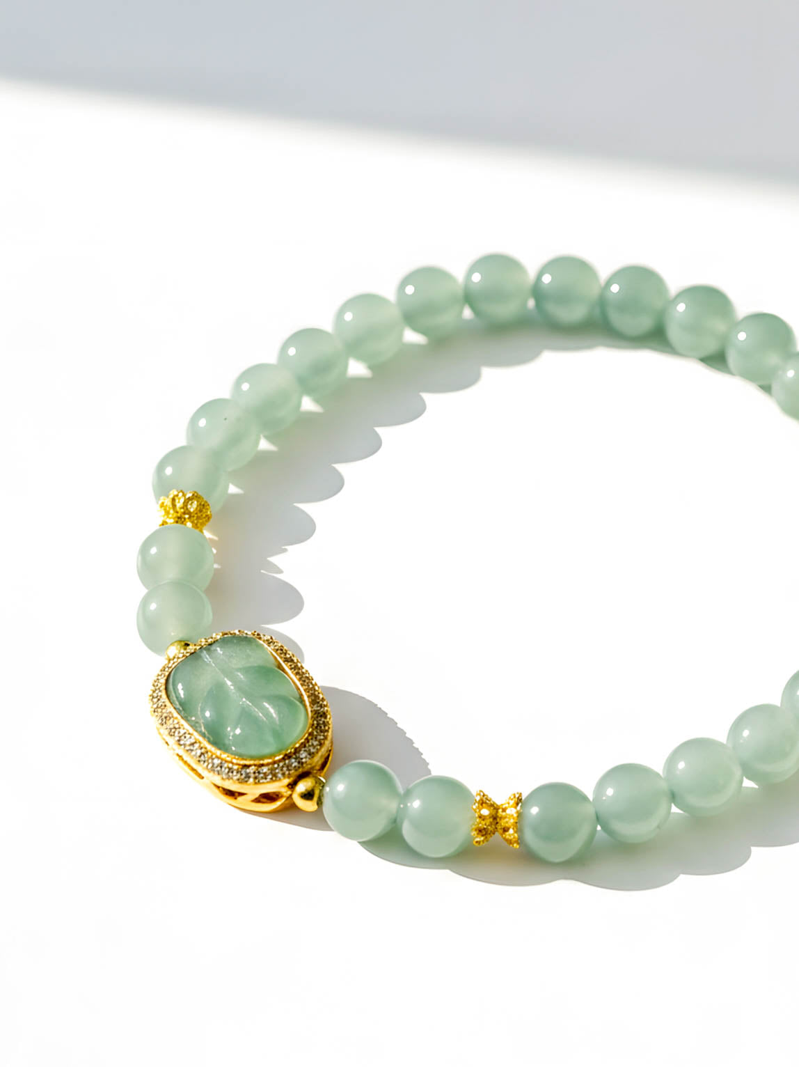 Green beaded bracelet with a gold clasp on a white background