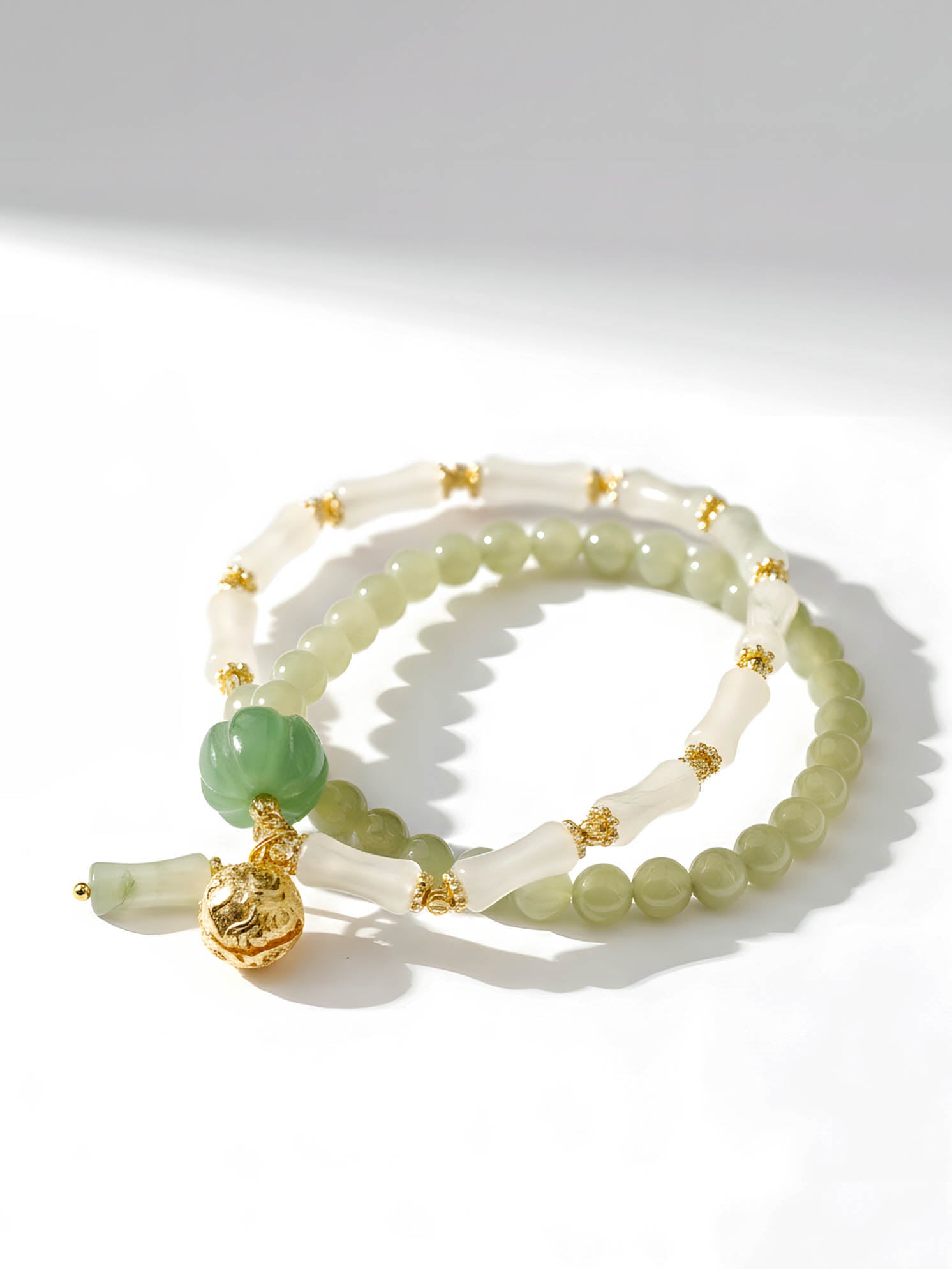 Two jade bracelets with gold accents on a white background