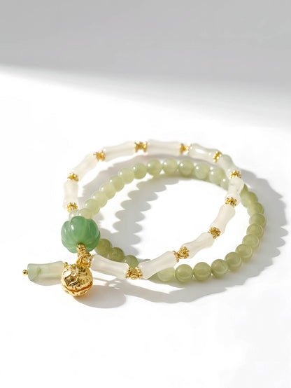 Two jade bracelets with gold accents on a white background