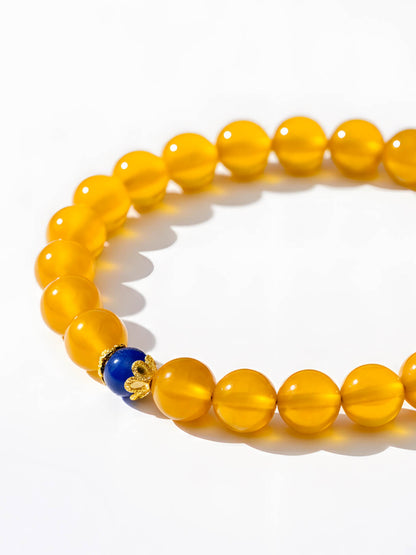 Yellow beaded bracelet with a blue and gold accent bead on a white background