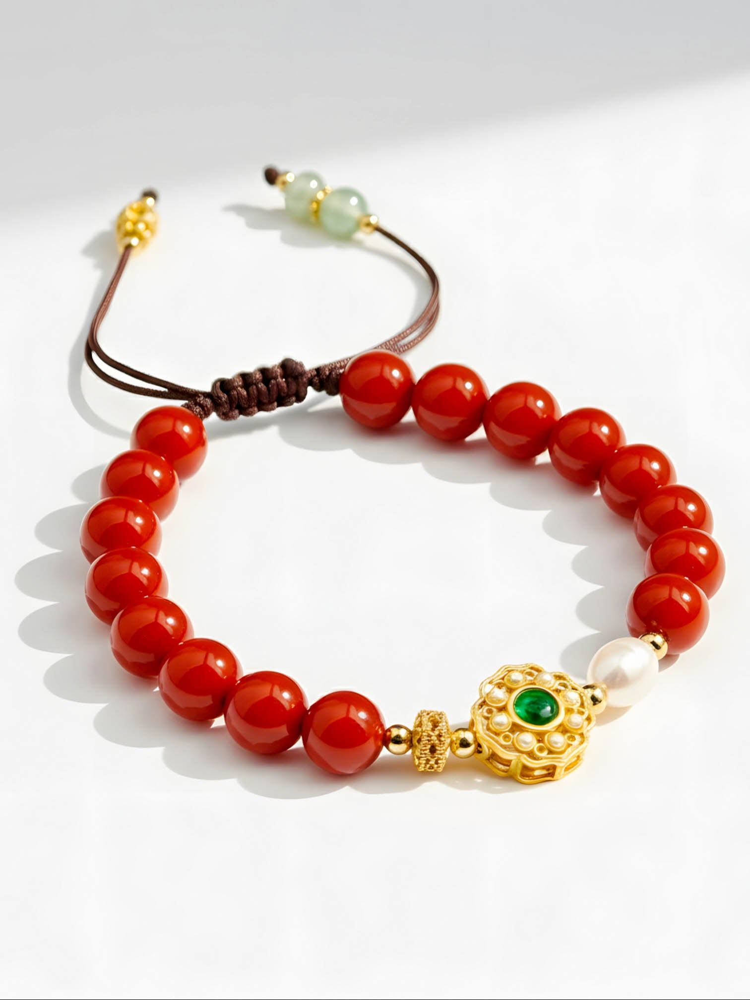 Bracelet with red beads and gold accents on a white background