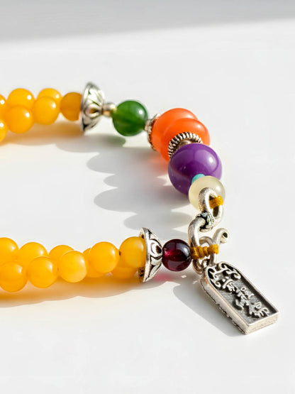 Colorful beaded bracelet with a silver charm on a white background