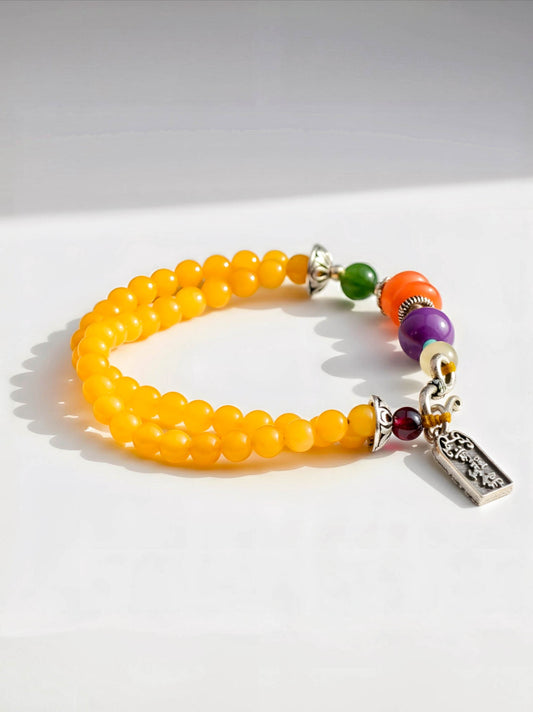 Multicolored beaded bracelet with a silver charm on a white background