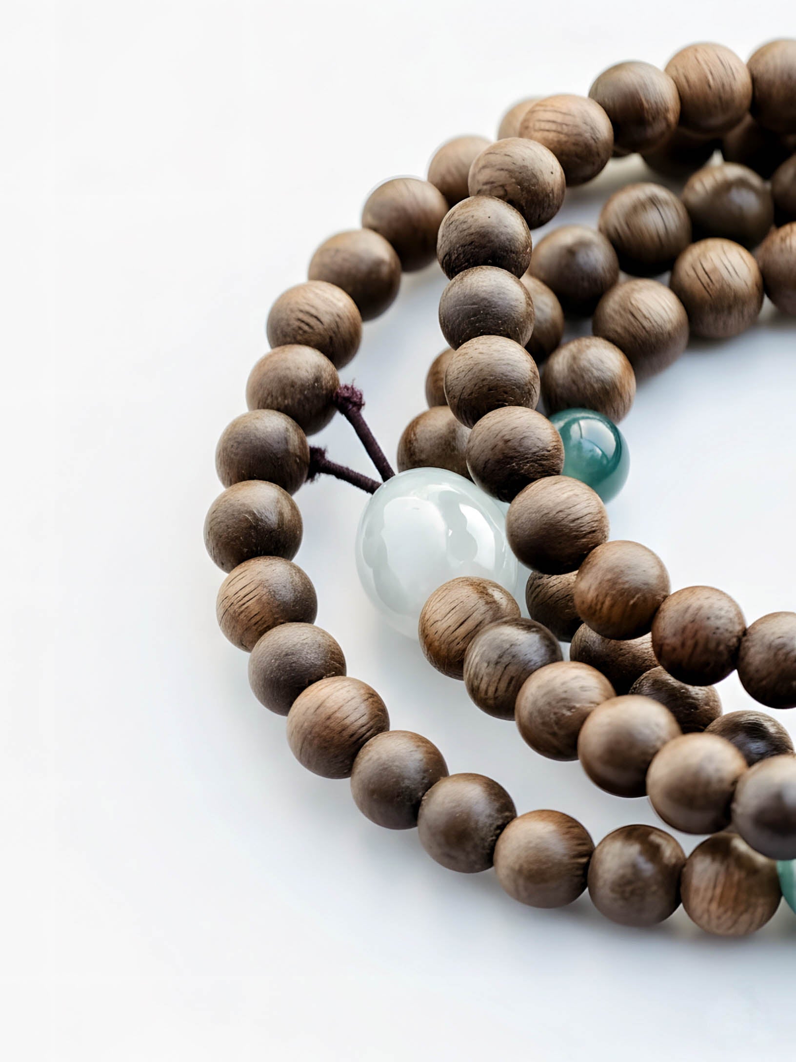 Wooden beaded bracelet with a green accent bead on a white background