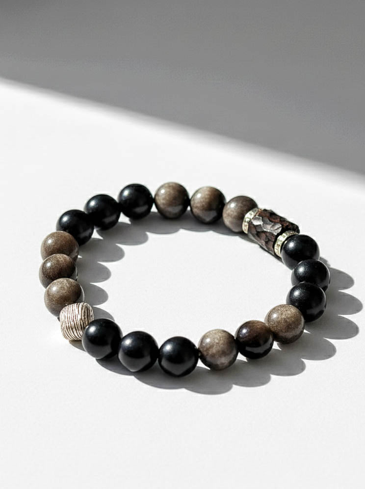 Beaded bracelet with black, brown, and gray stones on a white surface