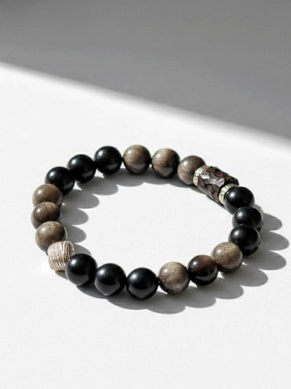 Beaded bracelet with black, brown, and gray stones on a white surface