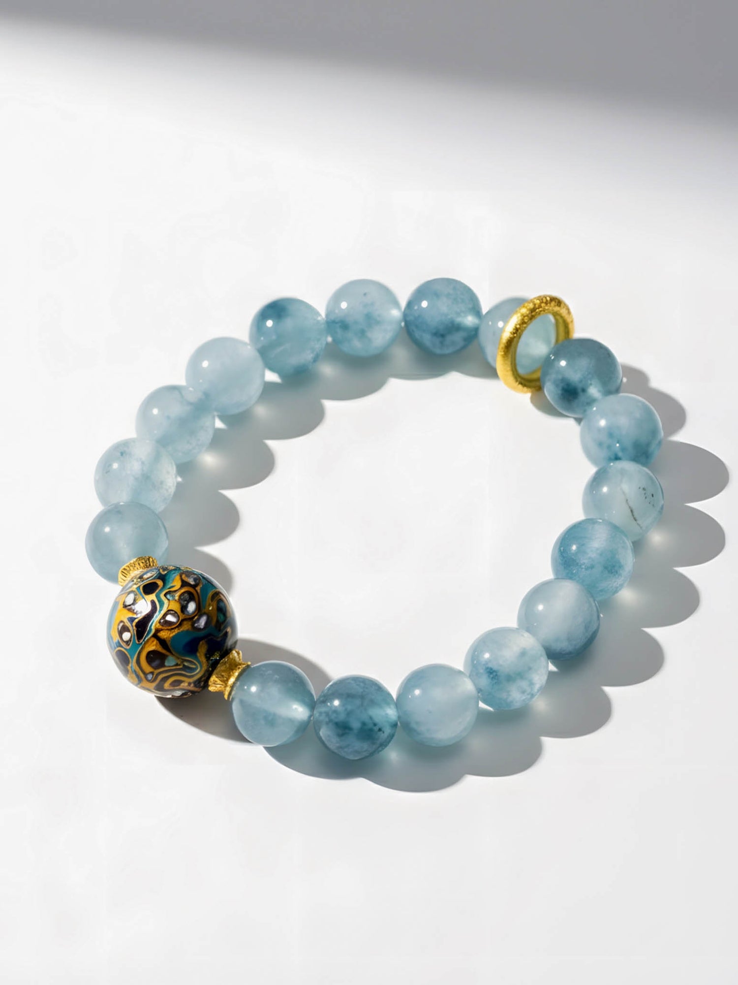 Blue beaded bracelet with gold accents on a white background