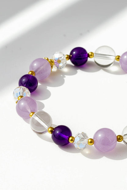 Necklace with purple, clear, and gold beads on a white background