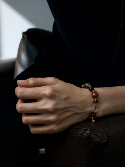 Close-up of a hand wearing a beaded bracelet on a dark surface