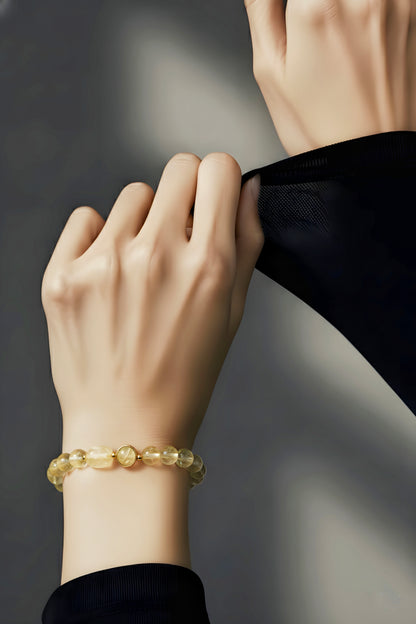 Close-up of a hand wearing a gold bracelet on a dark background