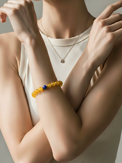 Person wearing a yellow beaded bracelet on a neutral background