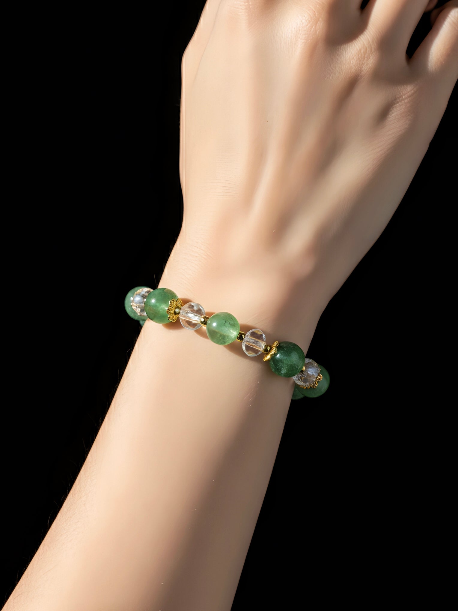 Green beaded bracelet on a wrist against a black background