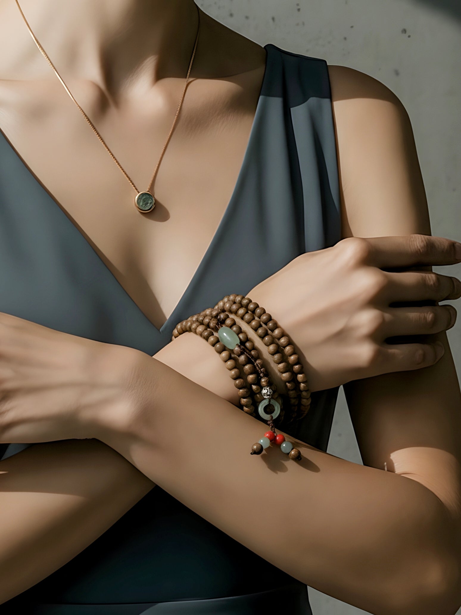 Close-up of a person wearing a necklace and bracelets on a neutral background