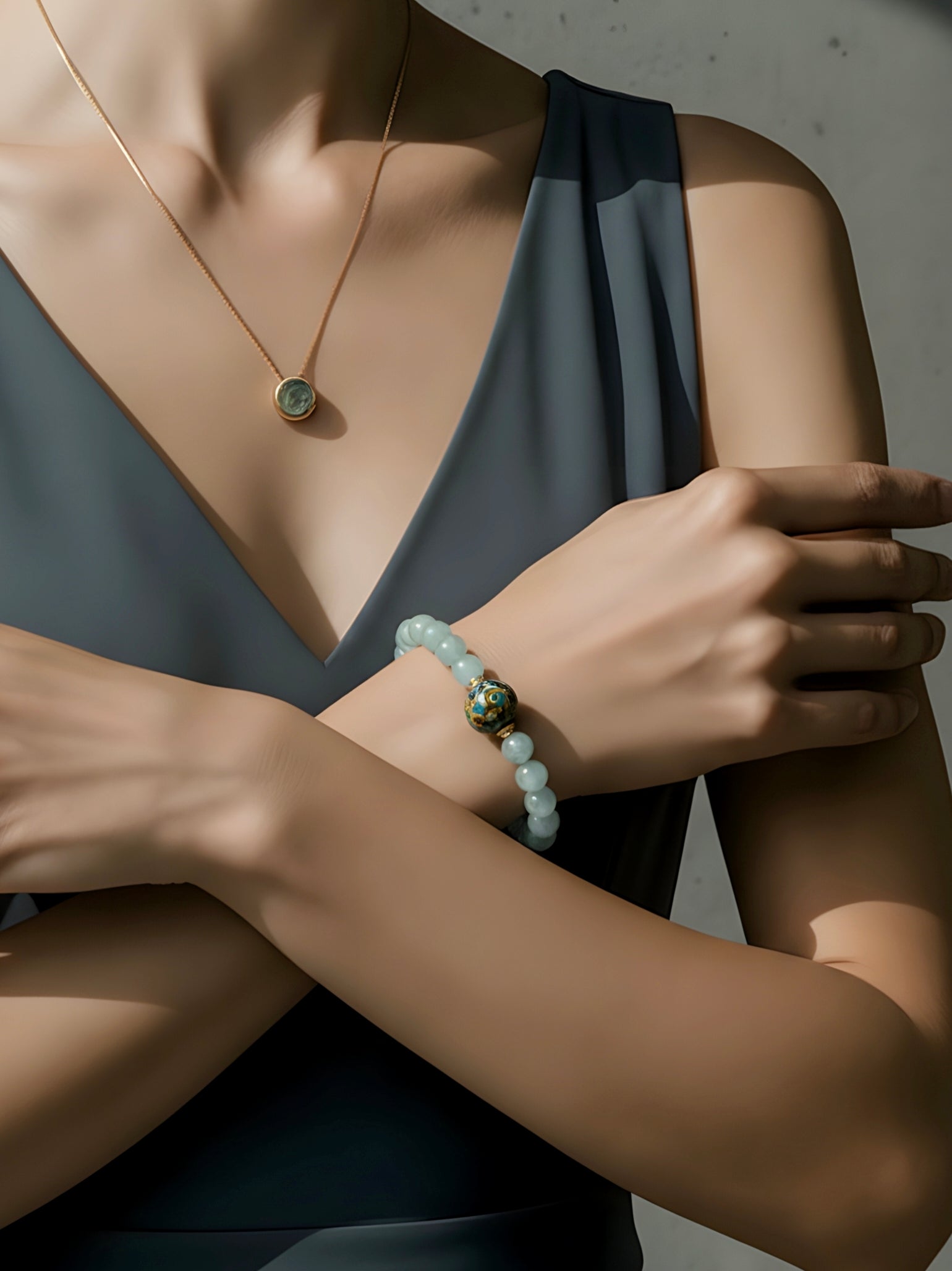 Person wearing a necklace, bracelet, and ring with a neutral background