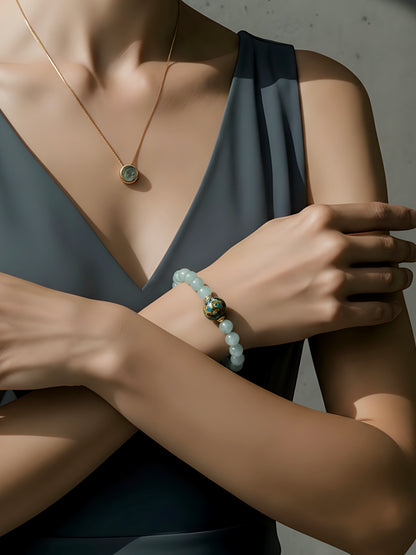 Person wearing a necklace, bracelet, and ring with a neutral background