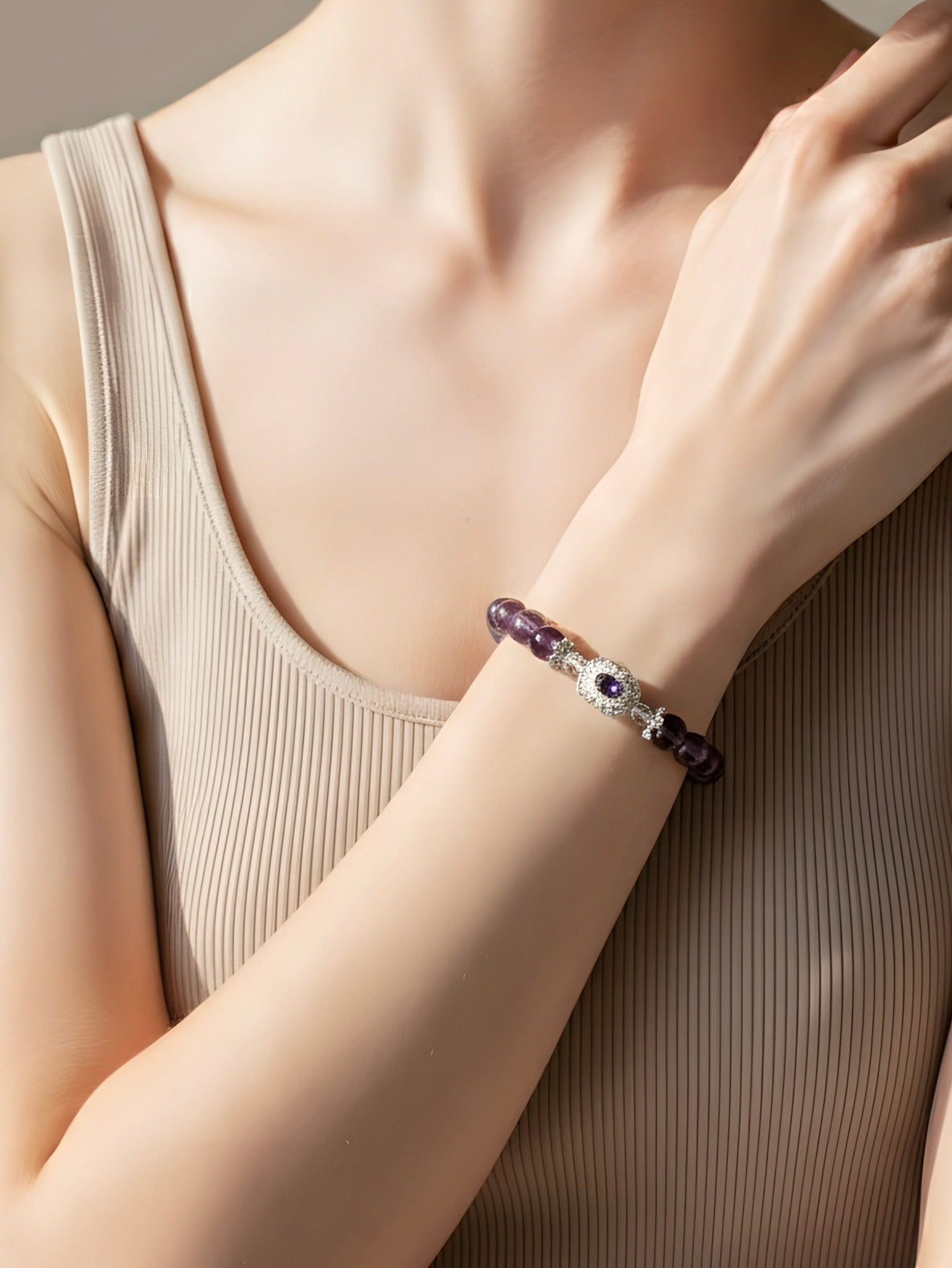 Close-up of a person wearing a bracelet with purple beads and a blue gemstone.