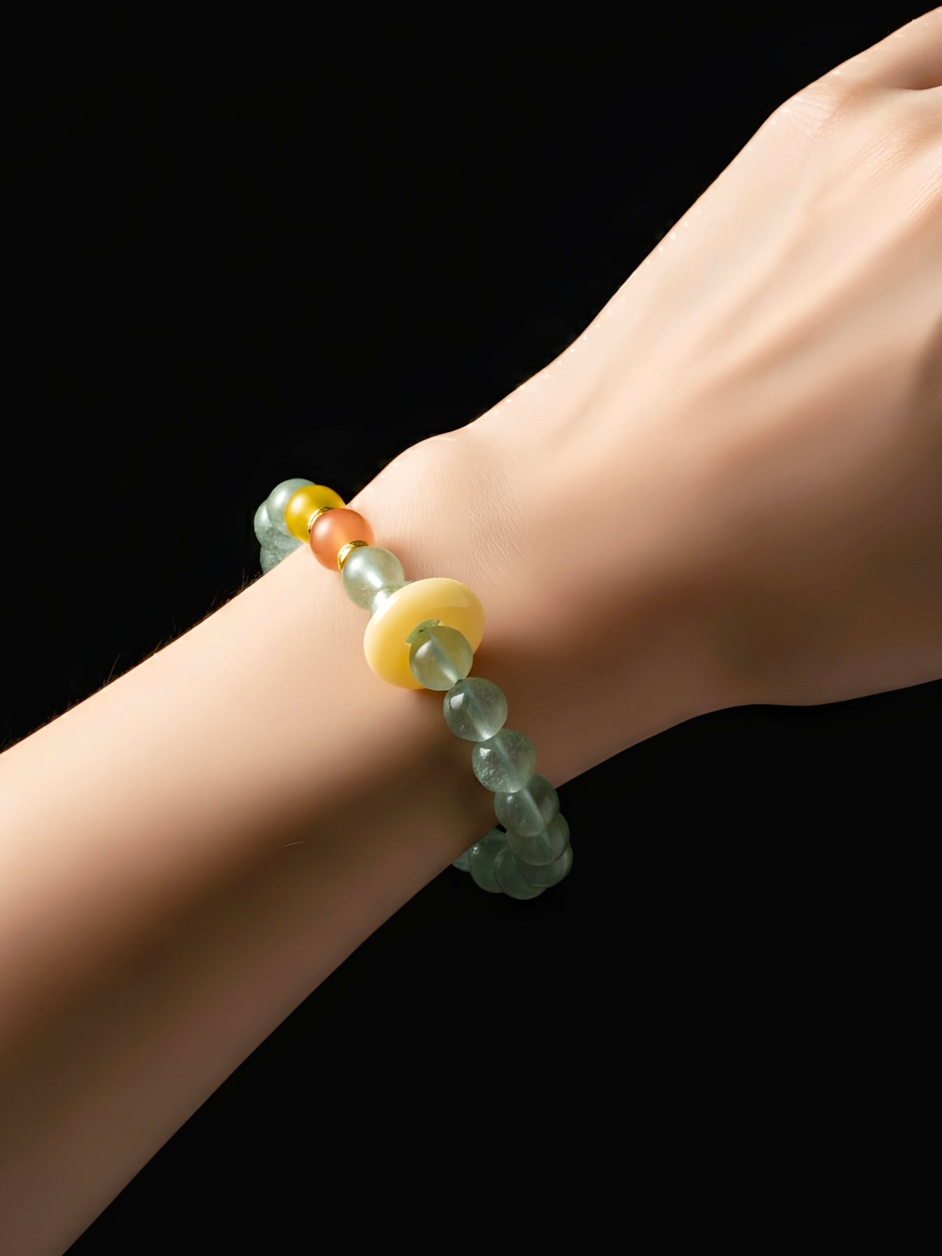 Bracelet with multicolored beads on a wrist against a black background