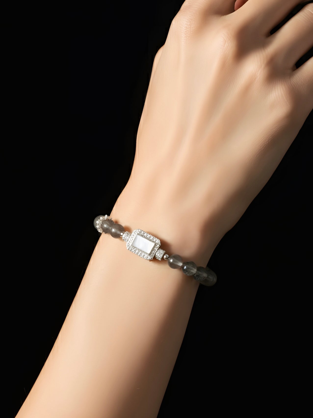 Bracelet with a diamond on a wrist against a black background