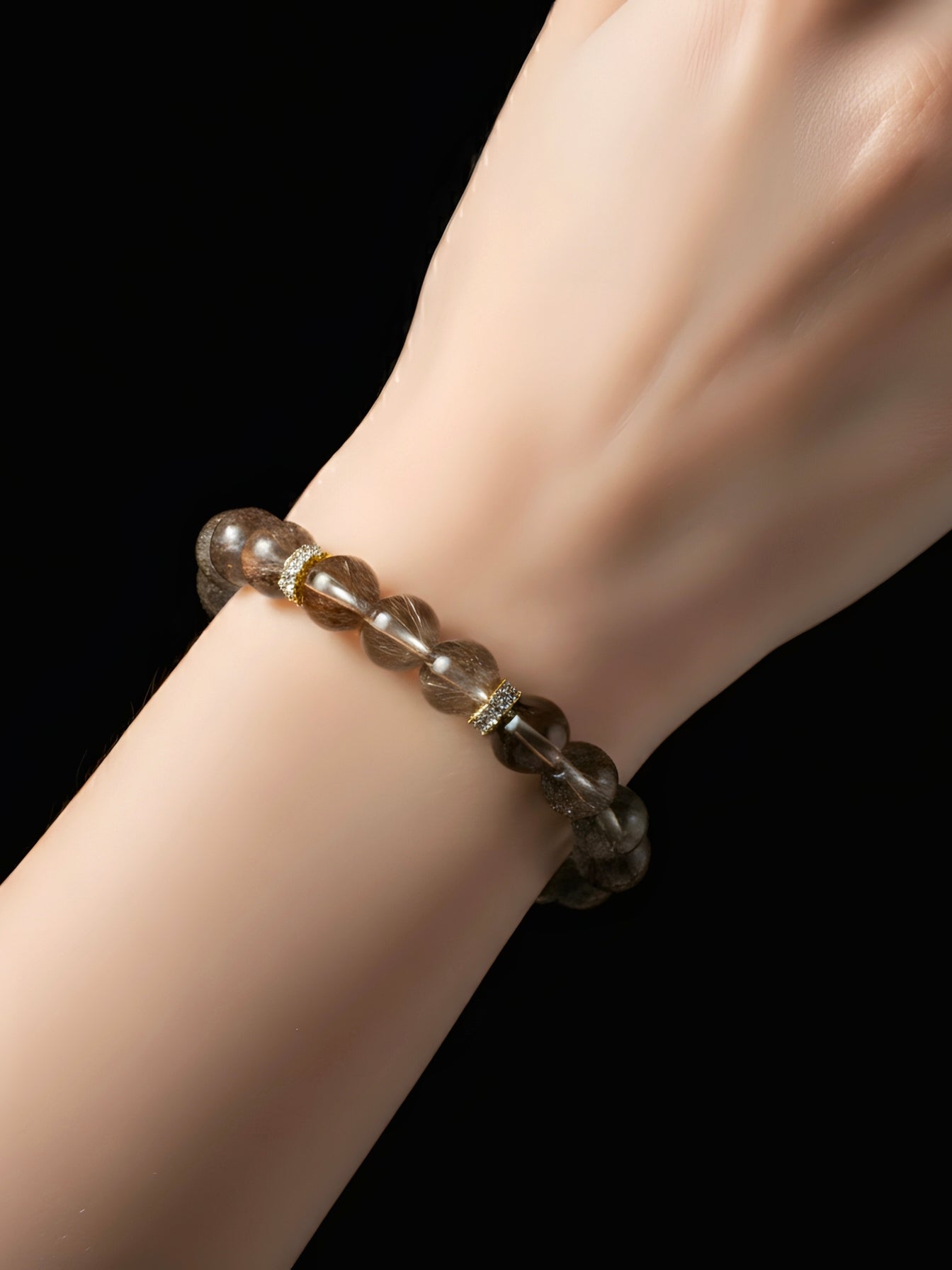 Bracelet with brown beads on a wrist against a black background