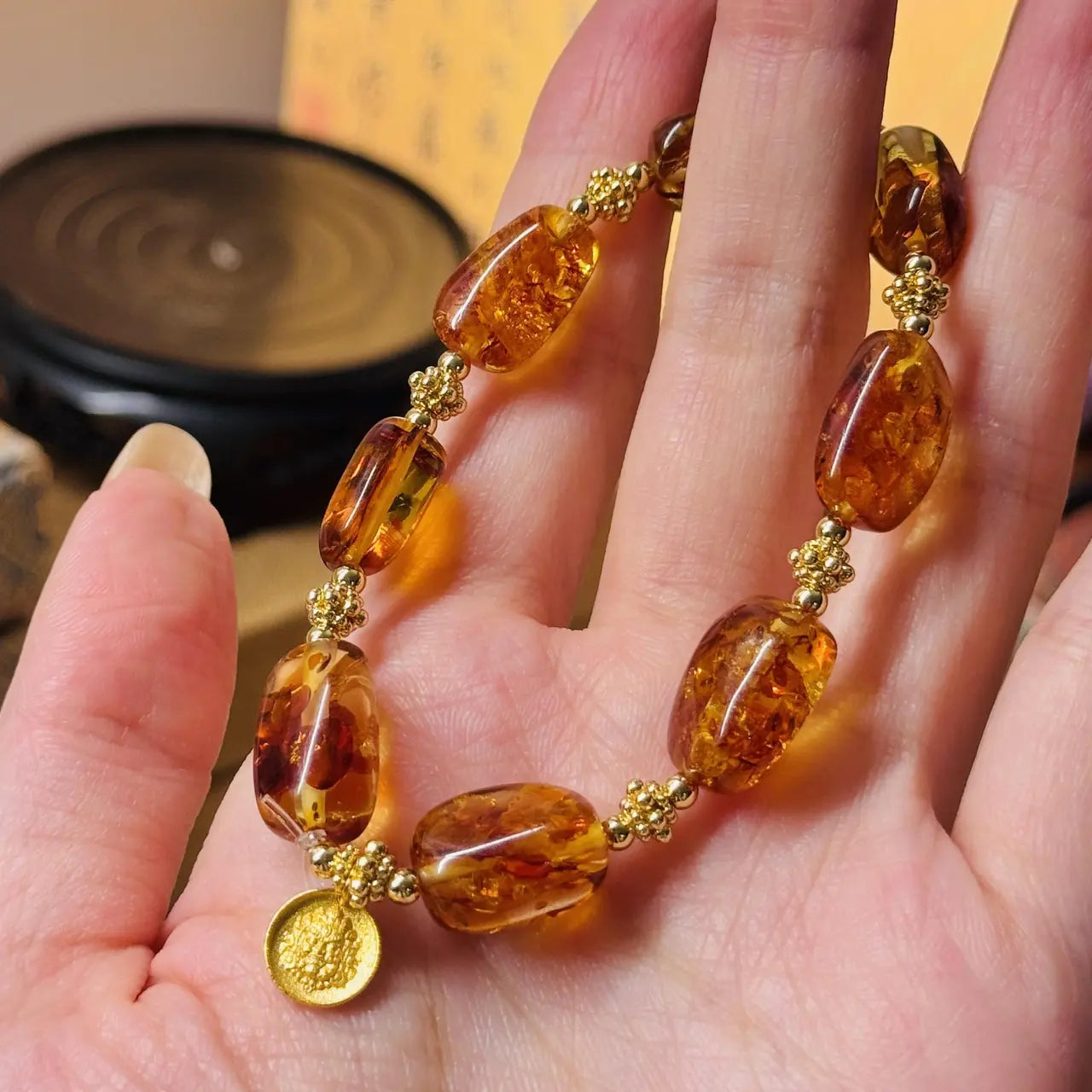 Amber bracelet with gold accents on a hand against a blurred background