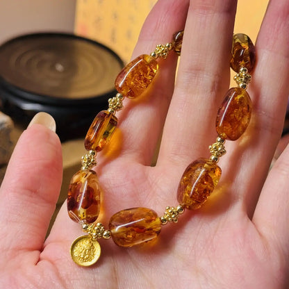 Amber bracelet with gold accents on a hand against a blurred background