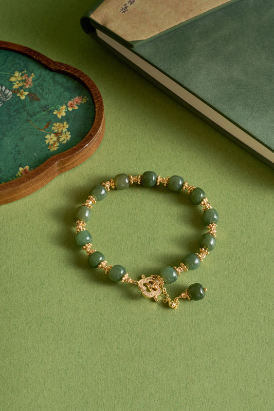 Green beaded bracelet with gold accents on a green surface