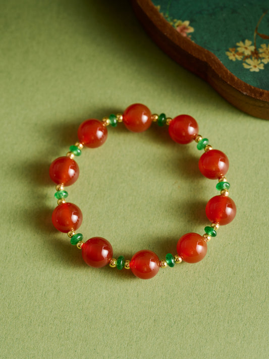 Red beaded bracelet with green accents on a green background